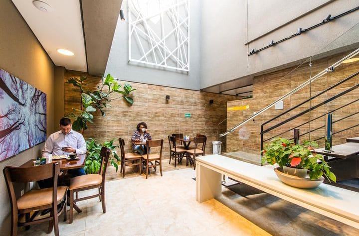 Área de espera moderna com pé-direito alto e decoração acolhedora