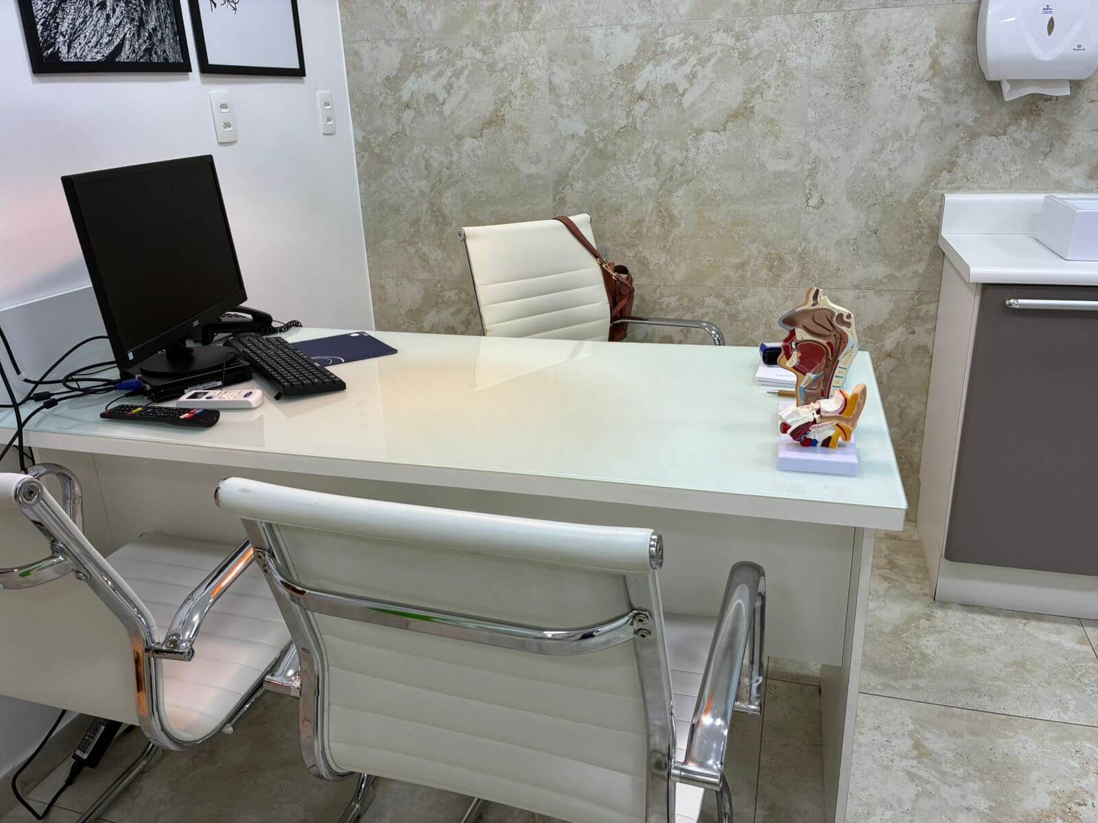 Mesa de consulta com modelos anatômicos e computador