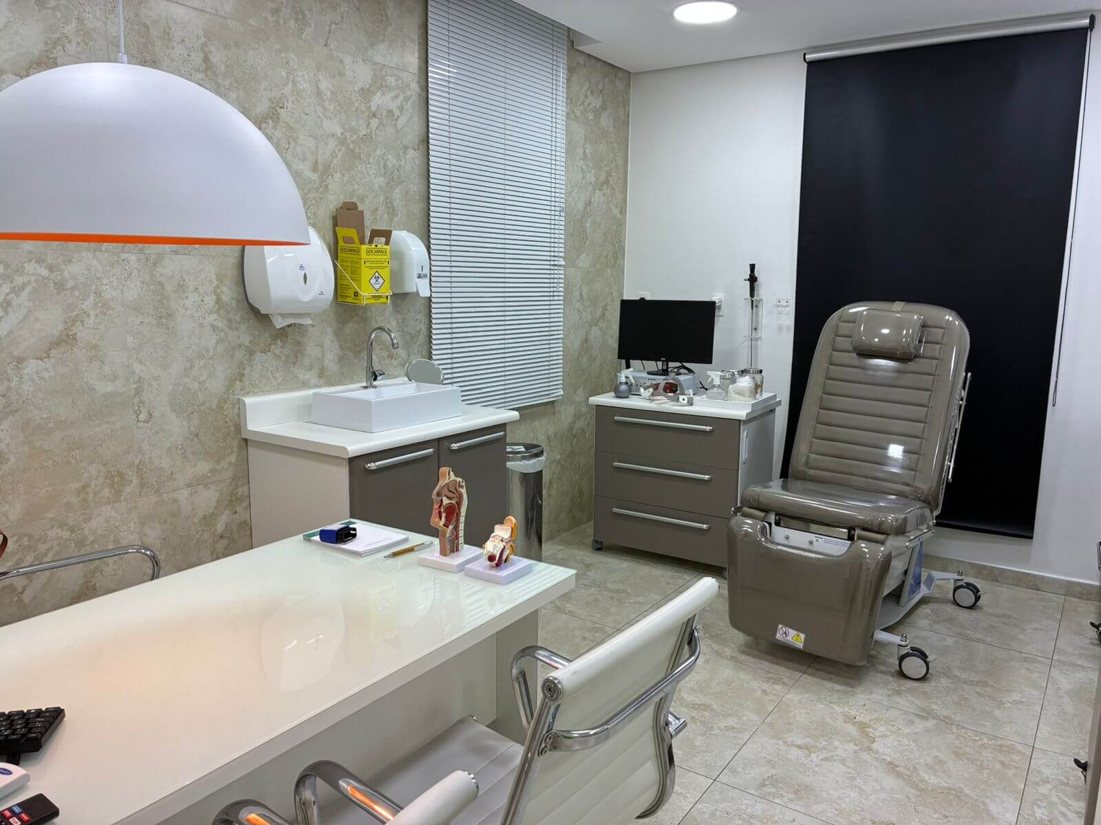Ambiente de atendimento com cadeira de exames e área de lavagem